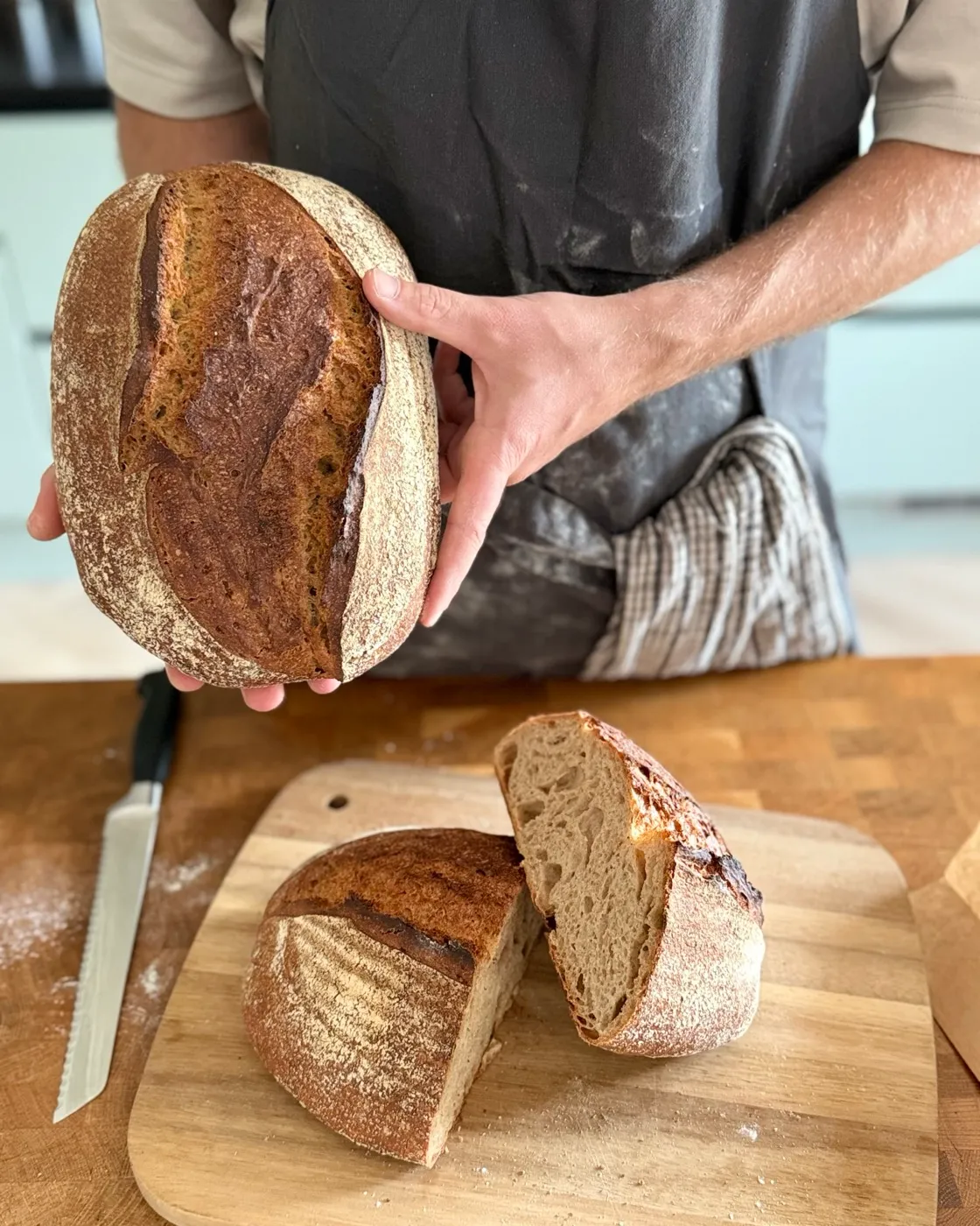Richard houdt een vers brood vast; op de werkbank een doorgesneden brood met open kruim.