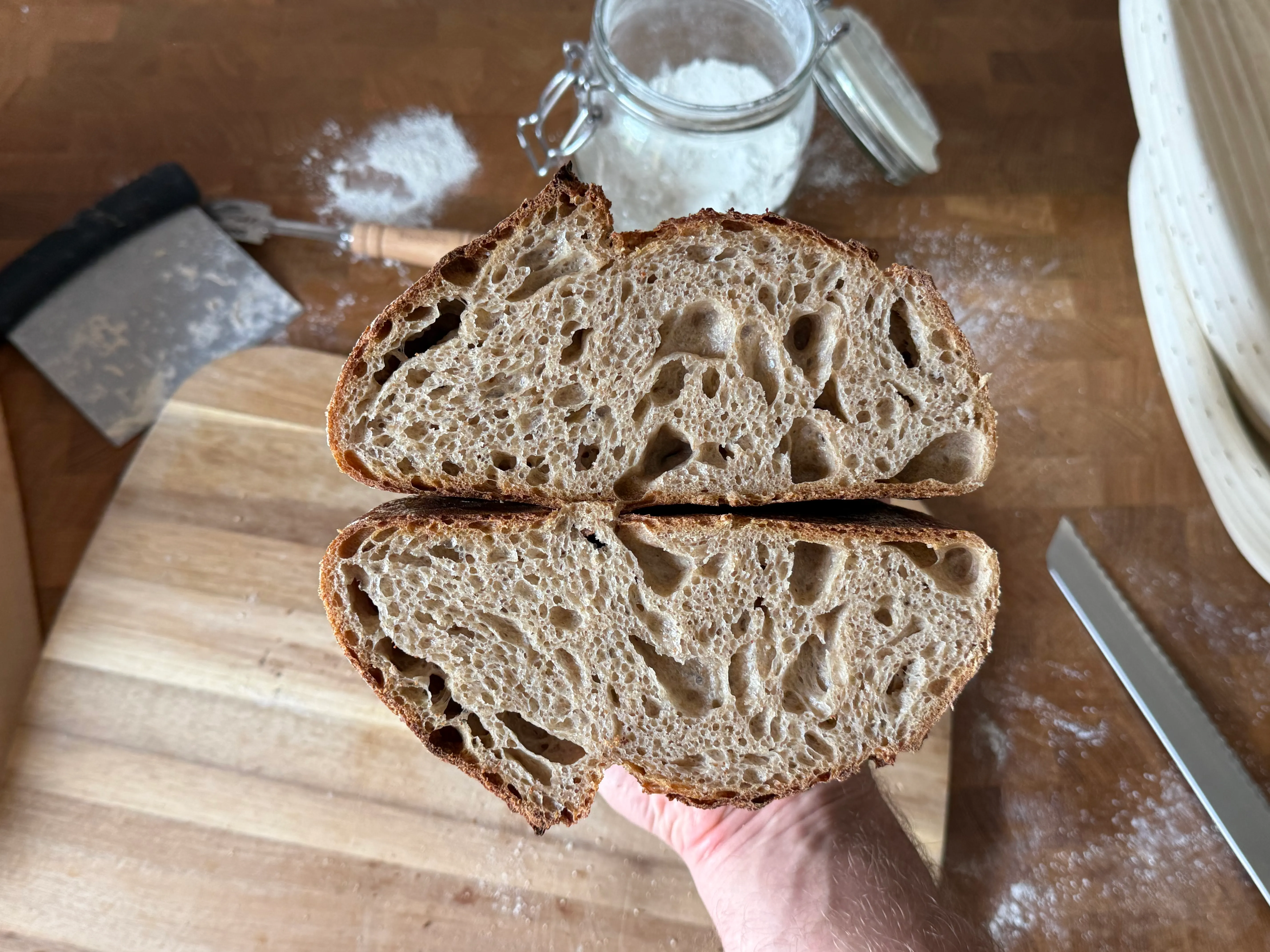 Een doorgesneden zuurdesembrood met open, grillig kruim.